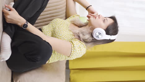 Vertical-video-of-Unhappy-young-woman-listening-to-music-with-headphones.